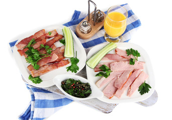 Bacon on plates on napkin on board isolated on white