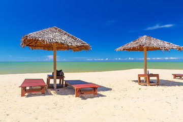 Tropical beach scenery with parasol and deck chairs in Thailand