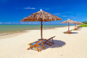 Tropical beach scenery with parasol and deck chairs in Thailand
