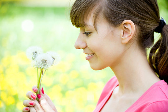 Happy girl admiring dandelions