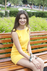 Brunette sitting on a bench in a summer park