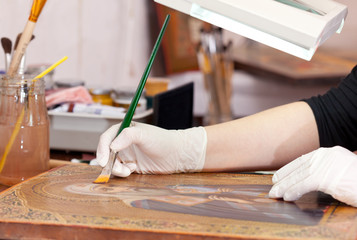 Art restorer works on old gilded icon