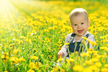 happy baby girl on  meadow with yellow flowers  on the nature