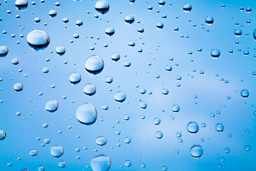 Macro photo of water drops on glass above blue blurred sky