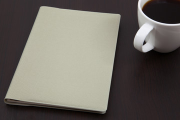 Cup of coffee on a wooden table with book
