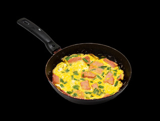scrambled eggs with sausage in a skillet over a black background