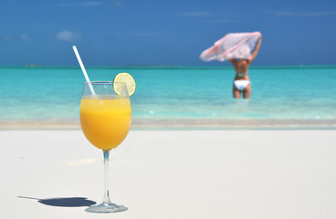 Glass of orange juice on the sandy beach of Exuma, Bahamas
