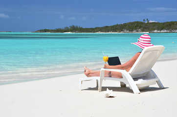 Girl with a laptop on the tropical beach. Exuma, Bahamas