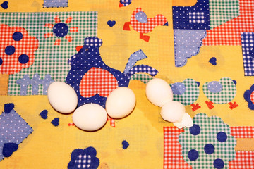 Huevos sobre un mantel patchwork con una gallina y sus pollos