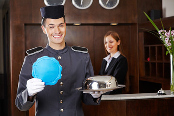 Hotelpage hält leeres Schild an Rezeption