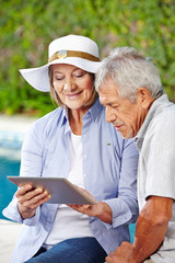 Senioren schauen auf Tablet PC im Urlaub