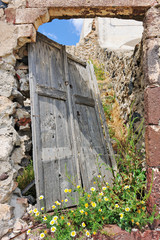 Broken door of abandoned house and overgrown plants in Pyrgos
