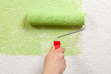 Maler streicht eine Wand mit Farbrolle