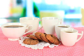 Cups of coffee with cookies on pink napkin on window background