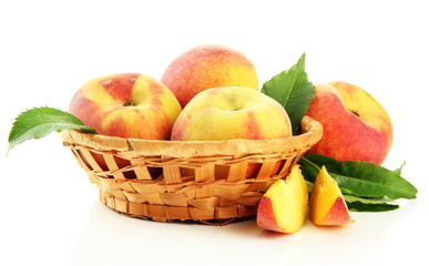 Ripe sweet peaches with leaves in basket, isolated on white