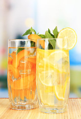 Glasses of fruit drinks with ice cubes on table in cafe