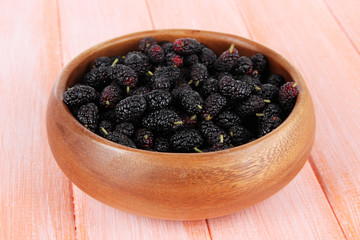 Fototapeta na wymiar Ripe mulberries in bowl on wooden background