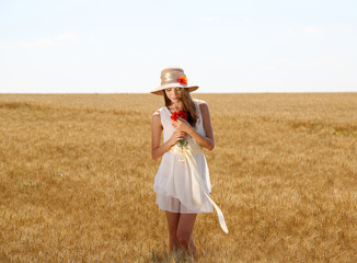 Portrait of beautiful young woman with poppies in the field