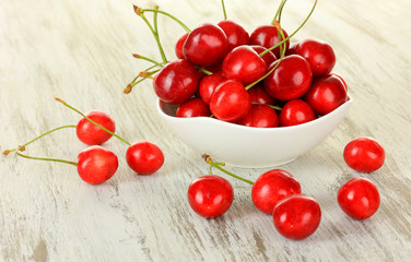Cherry berries in bowl on wooden table close up