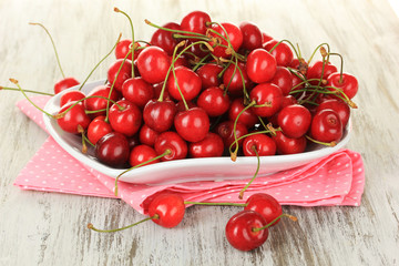 Cherry berries on plate on wooden table close up