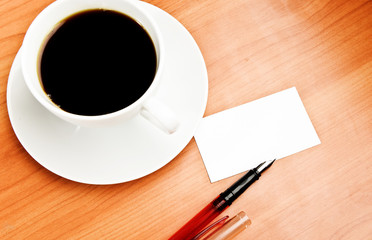 coffee cup, piece of paper and pen on the wooden table