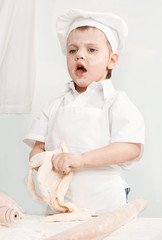 little boy preparing dough in a cap and apron