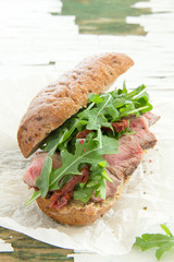 Bun with grilled roast beef and arugula.