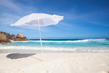 white sunshade and granit rocks at the beach