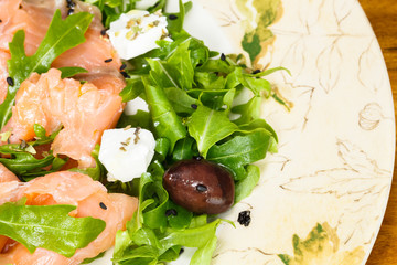 Smoked salmon with arugula salad, olives, cheese and sesame