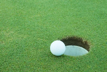 Afwasbaar Fotobehang Bol A golf ball very close to a hole