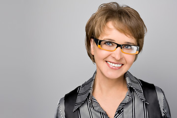 Portrait of the business woman in glasses on a grey background
