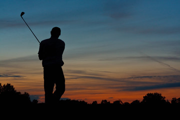 Golfer teeing off at dusk