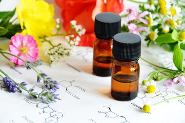 essential oils with herbal flowers on science sheet