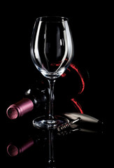 Wine Glass, wine bottle and corkscrew on a black reflective back