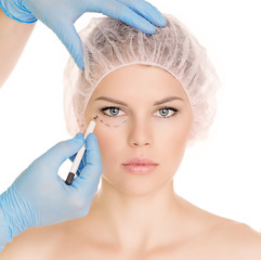 Plastic surgeon drawing lines over eyelid, isolated