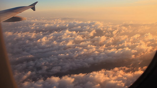 Clouds and sky as seen through window of an aircraft at sunrise.