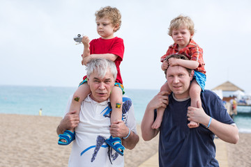 Grandfather and father giving two boys ride on shoulders
