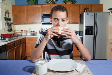 Mixed ethnicity teenager eating peanut butter jelly sandwich