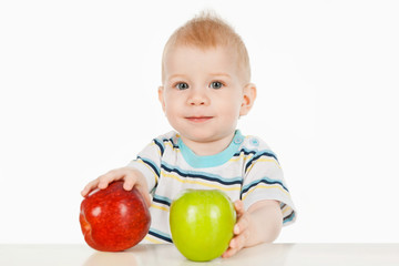 Fototapeta na wymiar A little boy sitting at a table with two apples