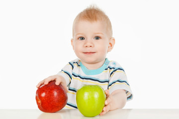 Fototapeta premium A little boy sitting at a table with two apples