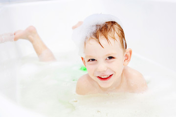 little boy swimming in bath and smiling