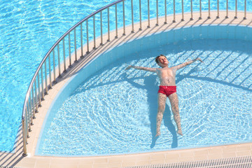 boy in the red trunks floating in the pool face up
