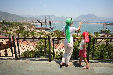 Obraz premium Mother and daughter walking along promenade and view ships