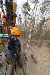 Boy climber stands on a platform on a tree