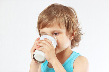 Little blonde boy drinking a fresh milk on white background