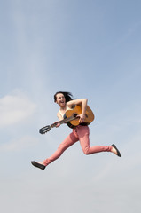 Frau springt mit Gitarre