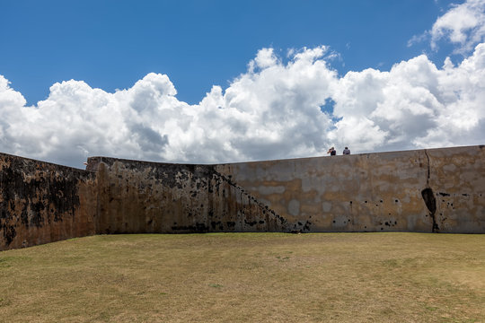 two people sit on wall at  El Morro in Old San Juan, PR