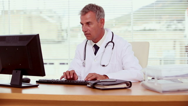 Smiling doctor using his computer