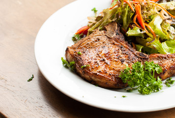 Pork chop with salad on table