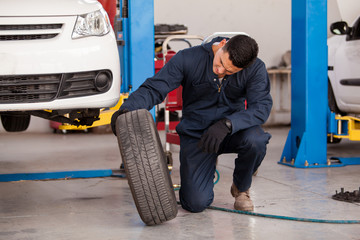 Fototapeta na wymiar Young mechanic inspecting a car tire at an auto shop